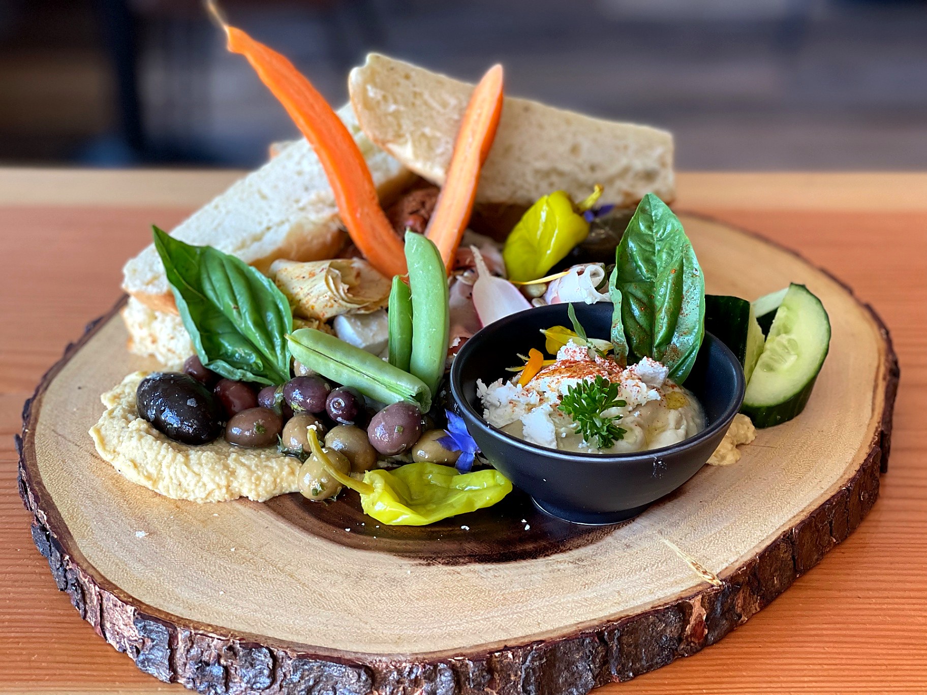 Mediterranean mezze board on live-edge wood with hummus, olives, focaccia and seasonal vegetables