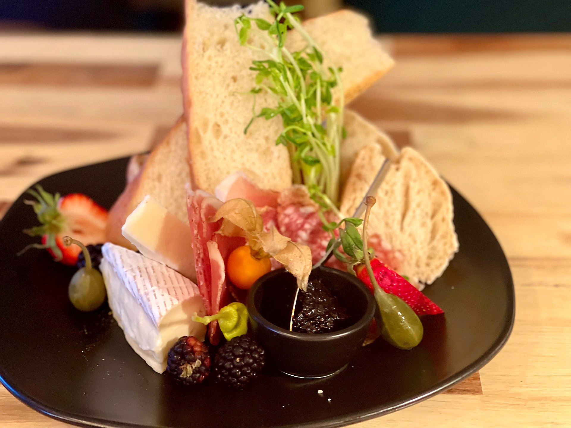 Charcuterie plate with prosciutto, salami, brie, berries and house preserves with sourdough