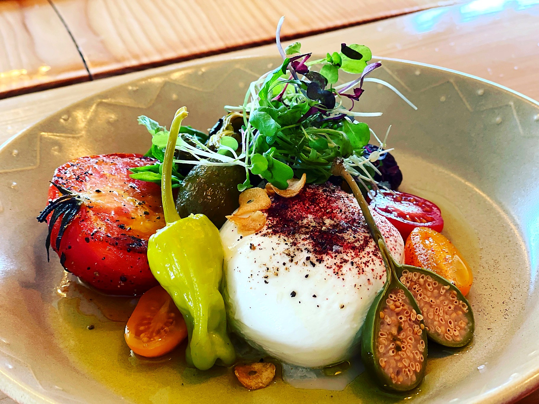 Burrata with heirloom tomatoes, shishito peppers, capers and microgreens dusted with sumac