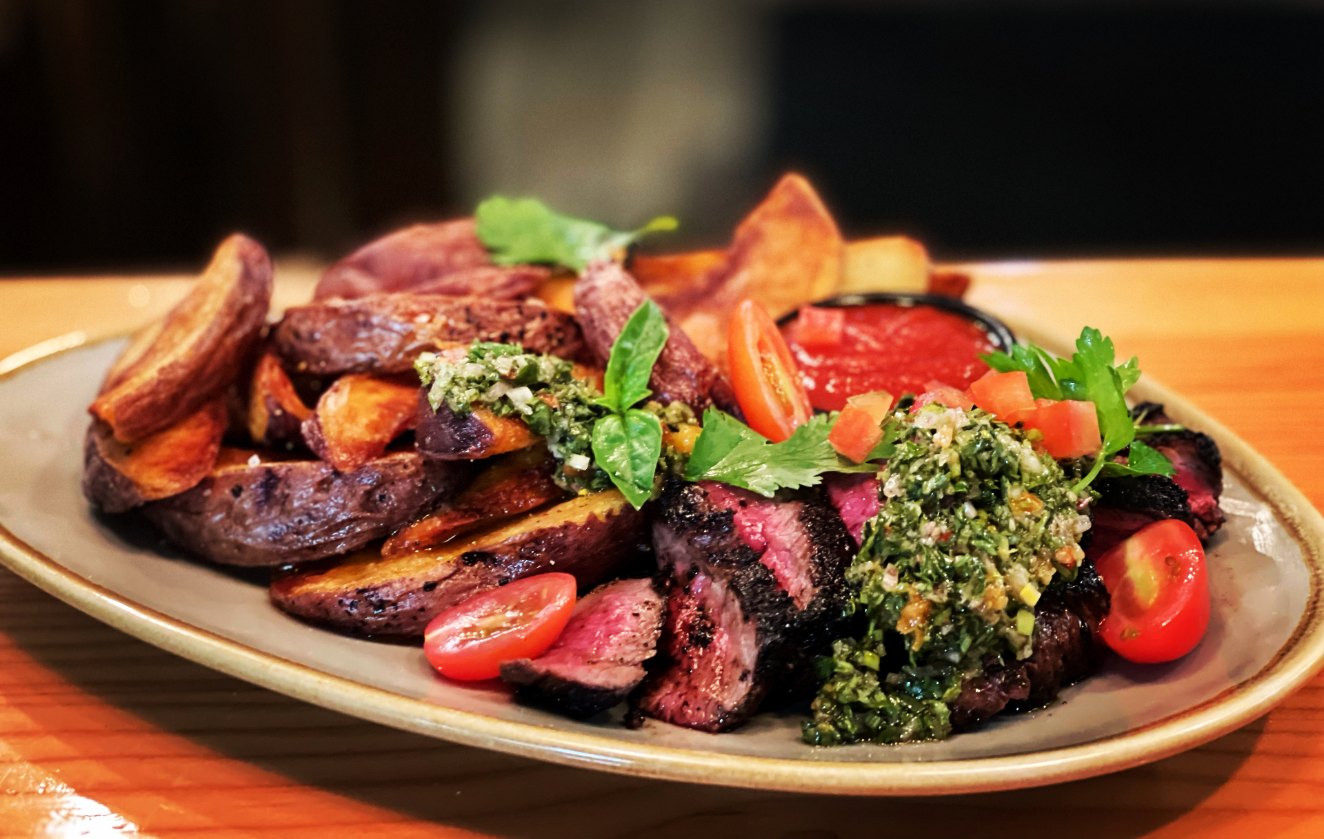 Grilled flat-iron steak with chimichurri, blistered tomatoes and crispy potato wedges